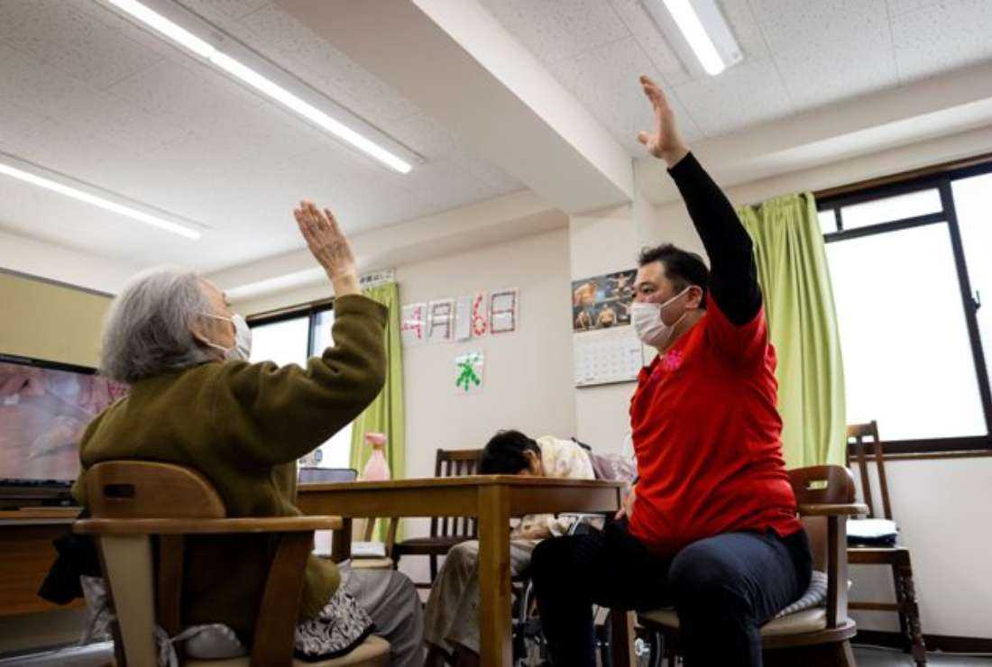 An elderly Japanese woman (left) exercises at a day care facility for senior citizens in Tokyo on April 6, 2022