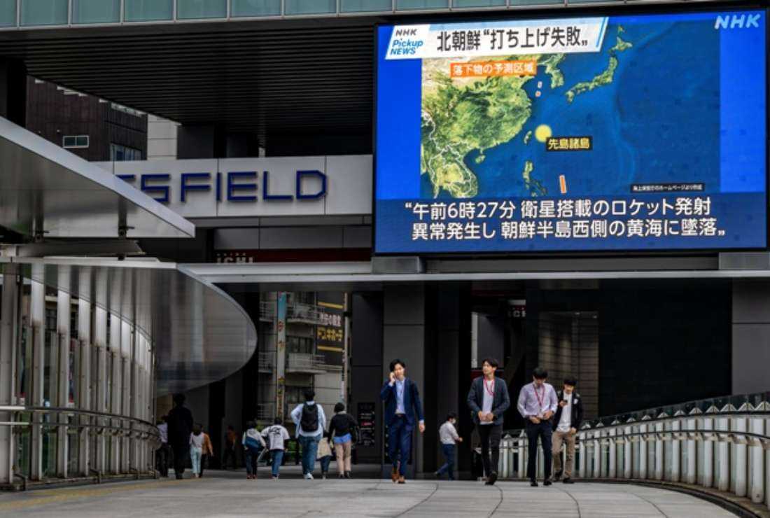 Pedestrians walk past a large video screen showing a map of the region during a news update in Tokyo on May 31 after North Korea launched a spy satellite that crashed into the sea