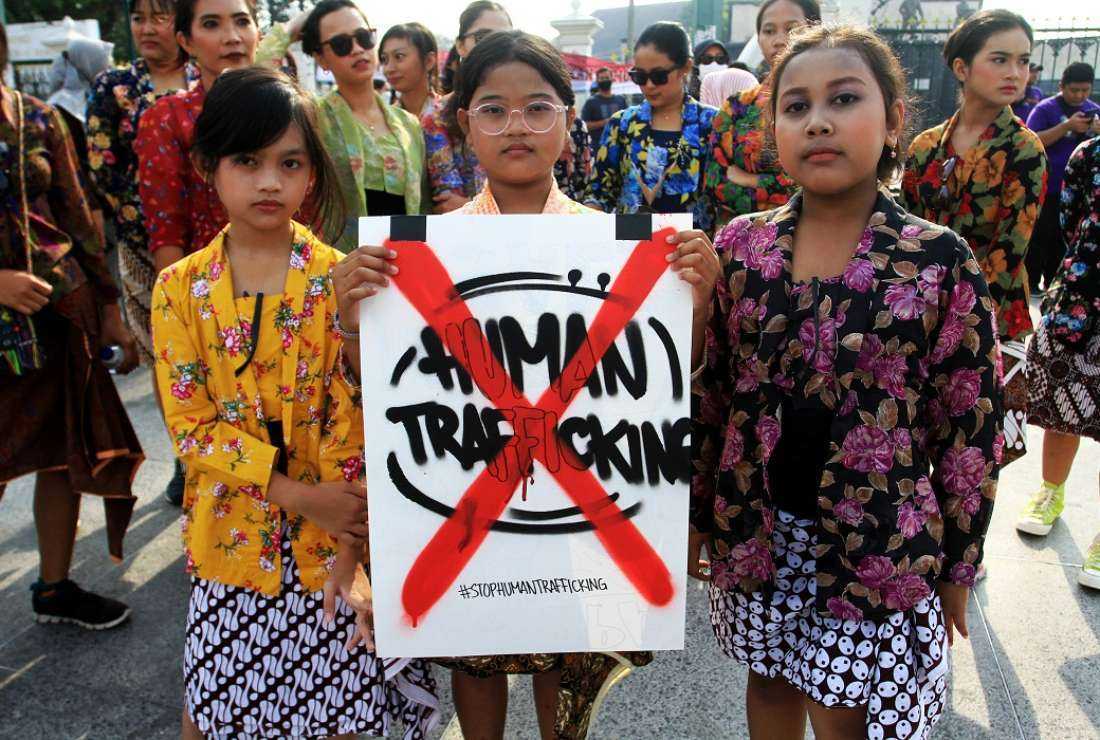 Youths pose with a placard during a protest to mark the World Day against Trafficking in Persons, in Yogyakarta, Indonesia, in this July 31, 2022 file photo. Indonesian authorities on May 7 said they had secured the release of 20 of its nationals who were trafficked into Myanmar more than eight months ago to work a range of online scams