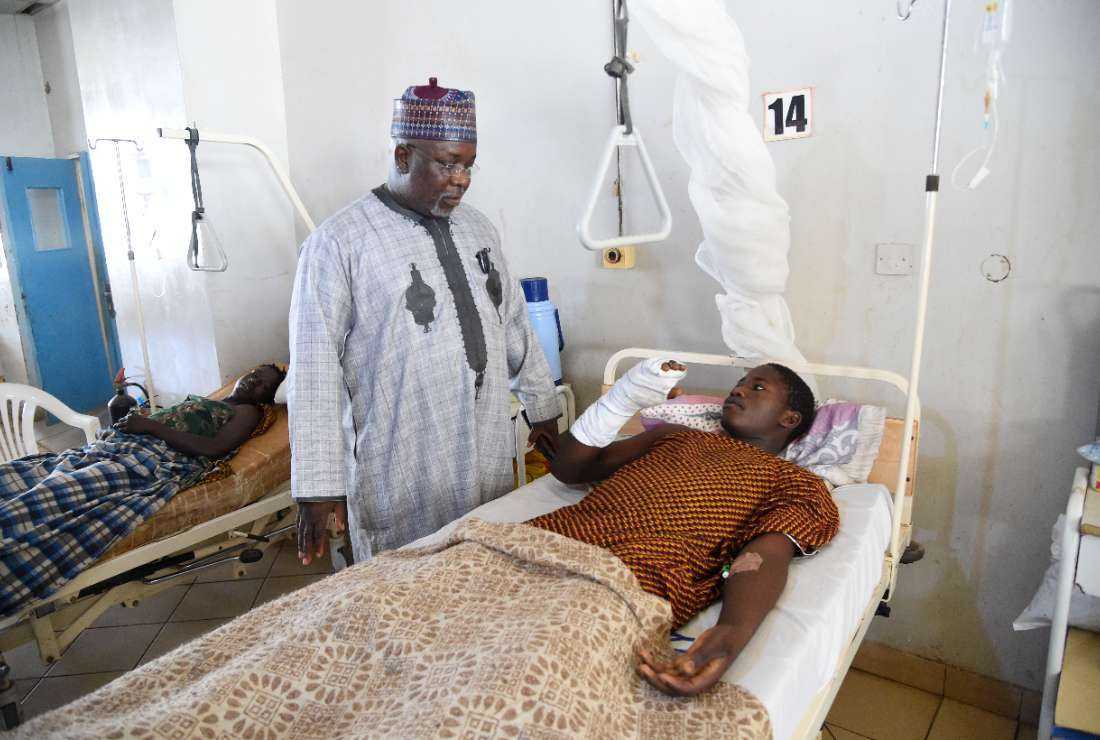 Chairman of Kanam district Yusuf Dayyabu Garga (left) tends to Yahaya Musa (right), a survivor of bandit attacks, at the Jos University Teaching Hospital where Musa is receiving treatment for injuries in Jos, Plateau State in north-central Nigeria, on April 23, 2022