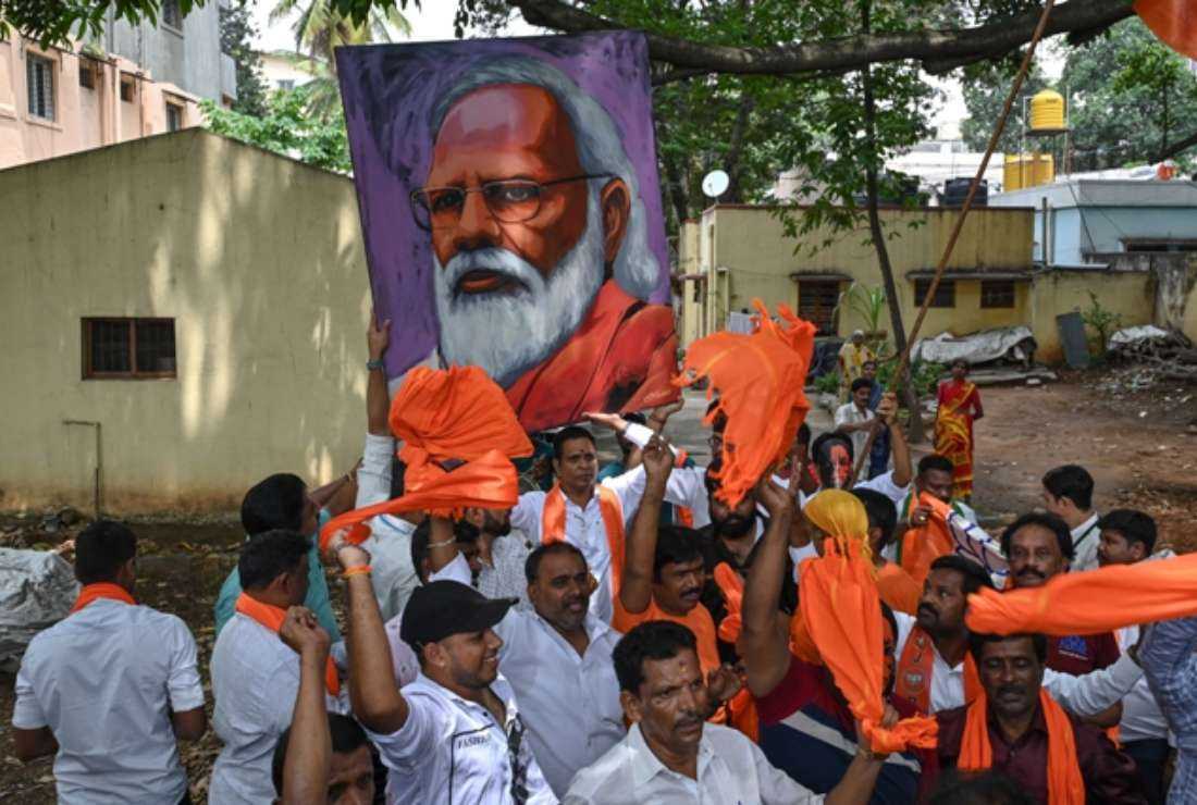Bharatiya Janata Party workers and activists carry a portrait of Indian Prime Minister Narendra Modi as they wait to see him during a road rally held in Bengaluru on May 6 ahead of the Karnataka Assembly election