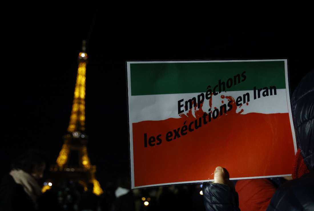 A protester holds a slogan reading in French 'Stop the executions in Iran' during a gathering to display the slogan 'Woman. Life