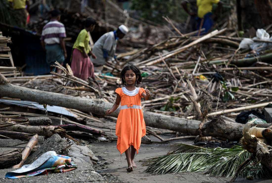 A girl walks past destroyed houses at Basara refugee camp in Sittwe on May 16, 2023, after Cyclone Mocha made landfall