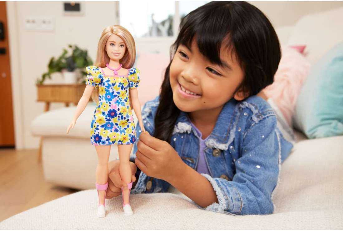 A girl is pictured with toy manufacturer Mattel's latest Barbie Doll with Down Syndrome