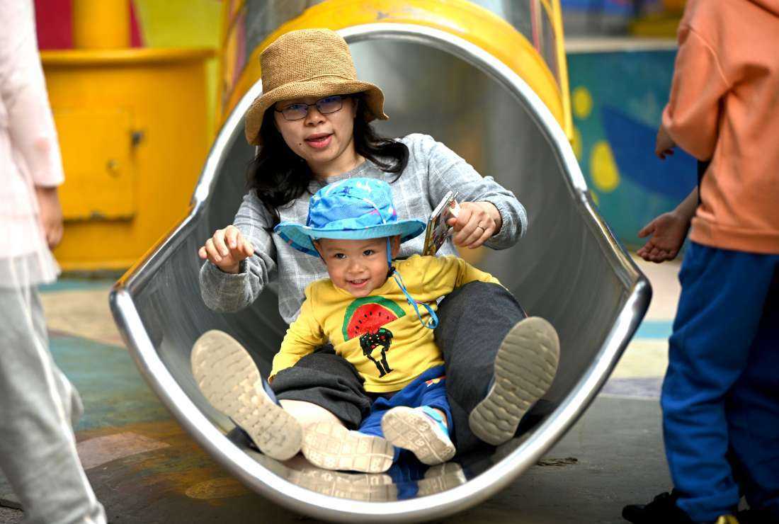 A mother and her baby play on a slide at Wukesong shopping district in Beijing on May 11, 2021