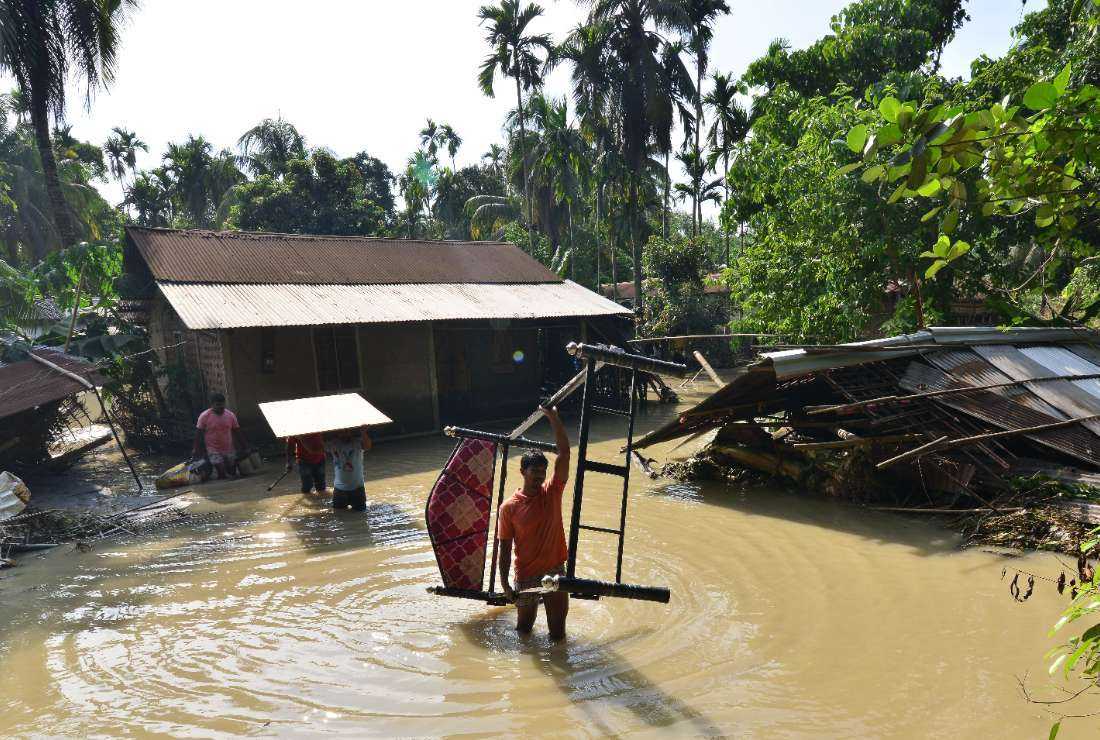 People removed furniture from their house in a flooded area following monsoon rains in Kenduguri village of Bajali district, some 105 Km from Guwahati in India's Assam state on June 23, 2023