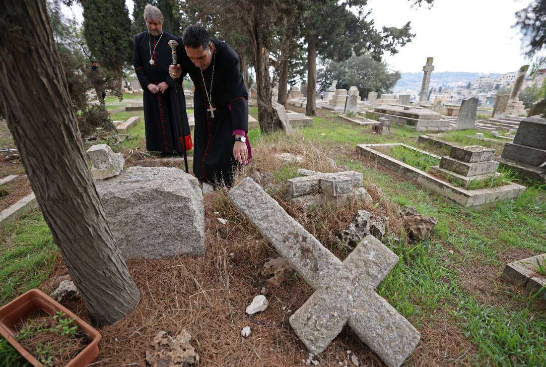 Hosam Naoum, archbishop and caretaker of the Protestant cemetery, inspects vandalised graves on Mount Zion outside Jerusalem's Old City on January 4