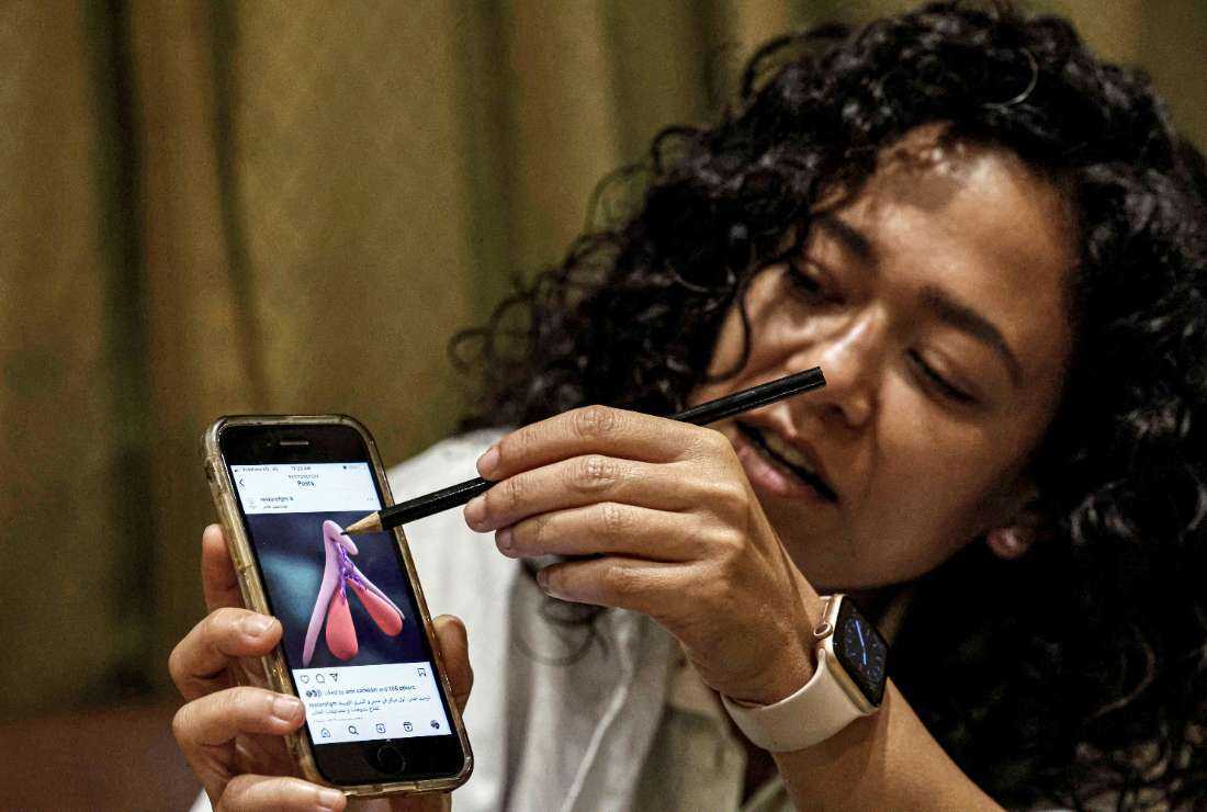 In this picture taken on June 11, physician Reham Awwad uses an illustration on a phone to describe the procedure of clitoral reconstruction surgery at the 'Restore FGM' clinic in Cairo