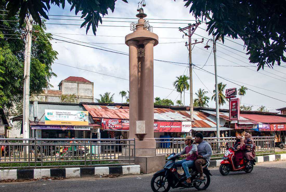 This picture taken on June 23 shows motorcyclists riding past a monument honoring the victims of a mass killing that took place in North Aceh on May 3, 1999, at Paloh Lada village in North Aceh