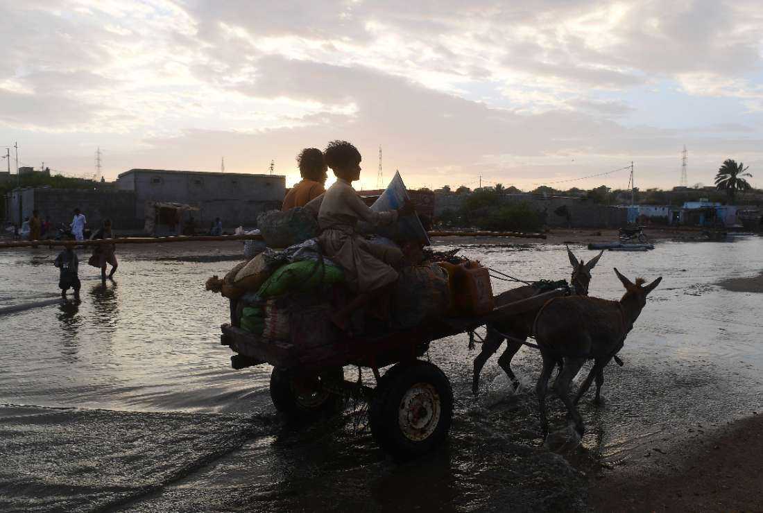 Fishermen on a donkey cart move to a safer place with their belongings at a fishing village on the outskirts in Karachi on June 14, ahead of cyclone Biporjoy landfall