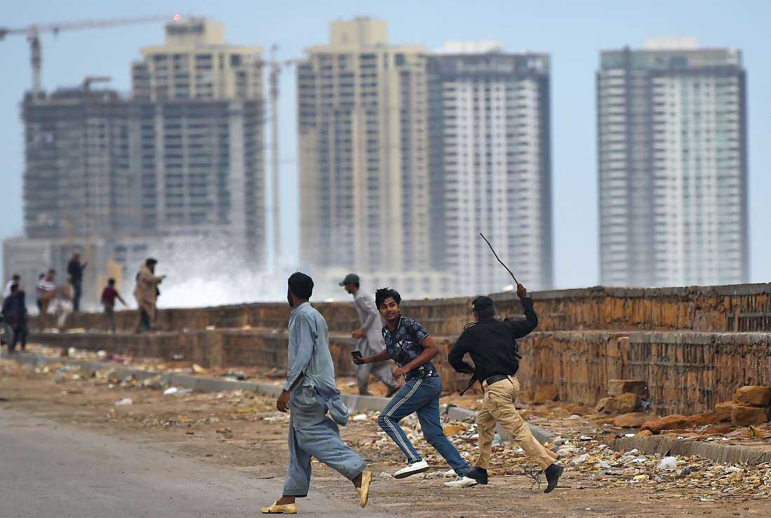 A policeman runs after a man as he instructs people to vacate a beach before the due onset of cyclone, in Karachi on June 13