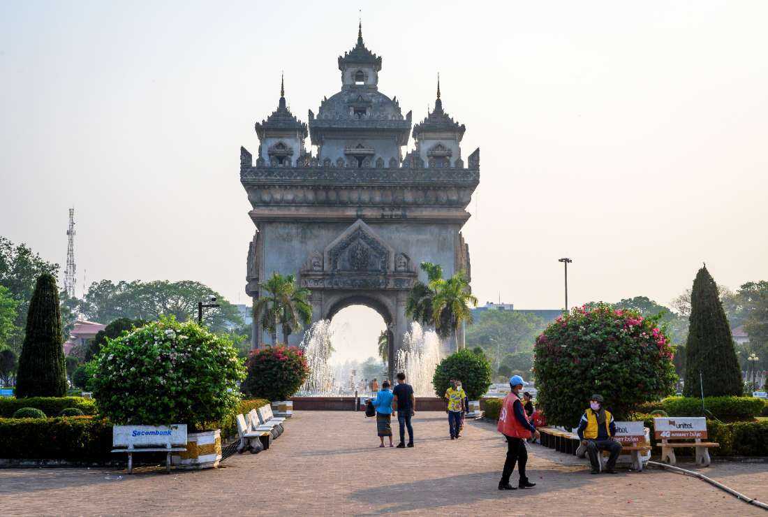 This photograph taken on March 12, 2020, shows people walking in front of the Patuxai war monument in the center of Vientiane