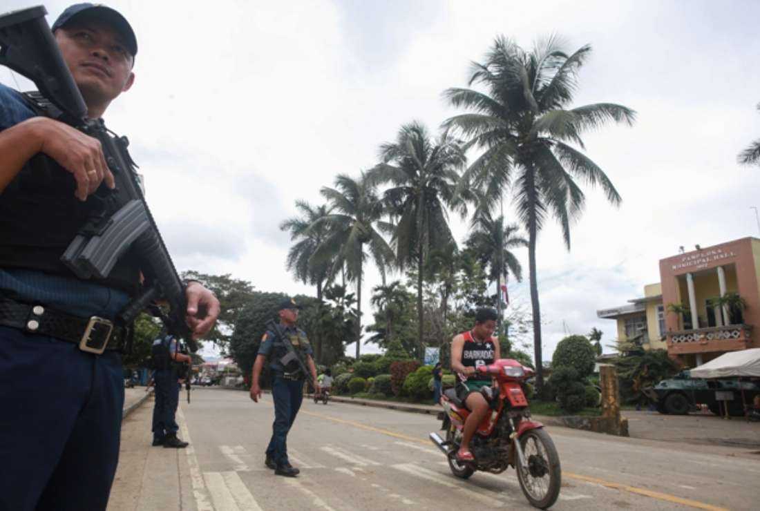 Armed policemen man a checkpoint in front of the municipal hall in Pamplona town in Negros Oriental on March 5. The Philippines military forces have been accused of killing a four-member family in the province