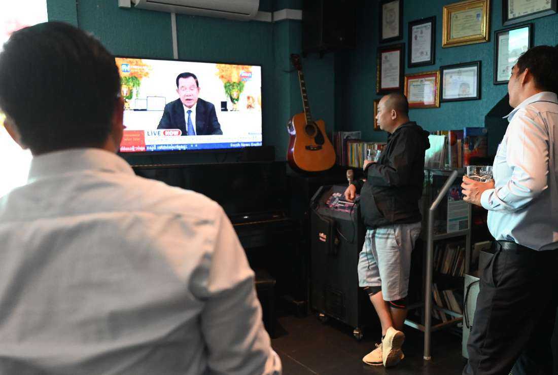 People watch as Cambodia's Prime Minister Hun Sen speaks during a special statement on television at a restaurant in Phnom Penh on July 26