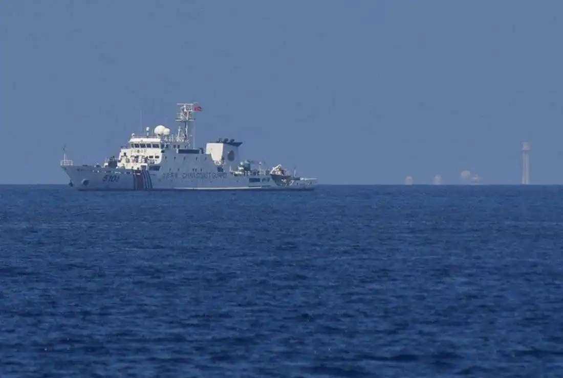 This photo taken on April 21 shows a Chinese coast guard ship patrolling before Subi reef (right) near the Philippine-occupied Thitu island in the disputed South China Sea