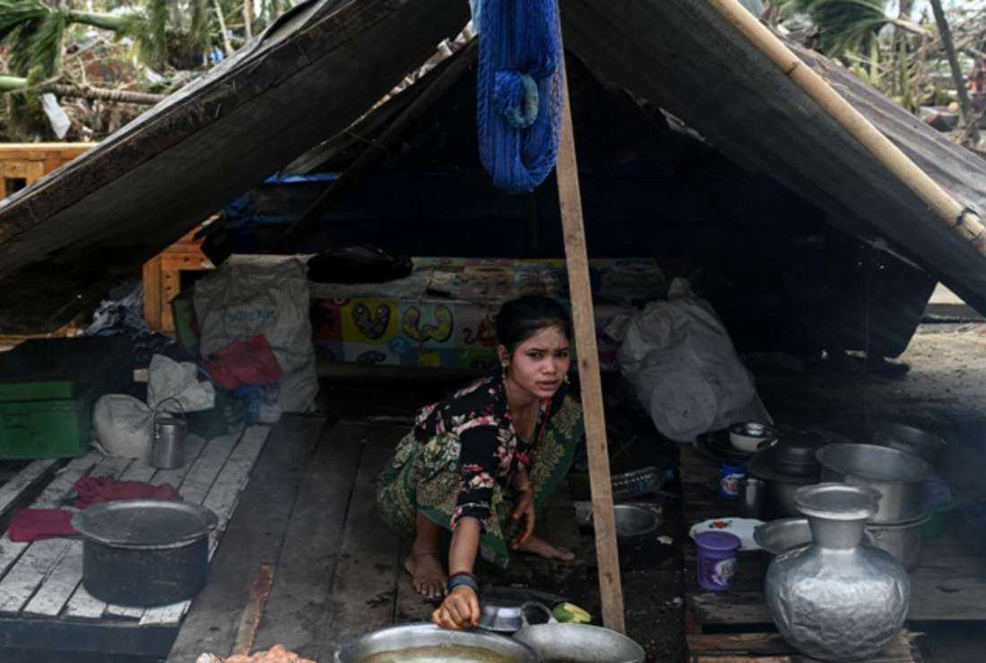A girl cooks under a makeshift tent used as shelter at Basara refugee camp in Sittwe on May 16. Cyclone Mocha has impacted 7.9 million people, rending many of them homeless