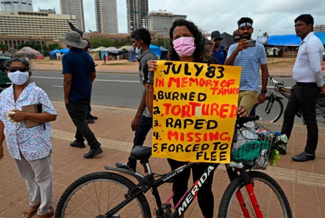 A demonstrator holds a placard during a protest to observe the anniversary of anti-Tamil rioting that started in the year 1983 also known as ‘Black July’ near the Presidential Secretariat in Colombo on July 24, 2022