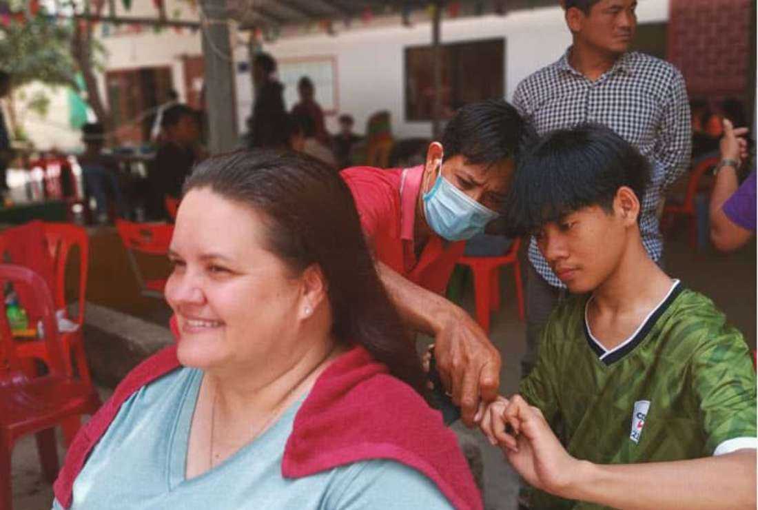 In preparation for Khmer New Year observed in April, Sambath, who is learning barbering at the Deaf Development Programme, gives Maryknoll Lay Missioner Julie Lawler a haircut