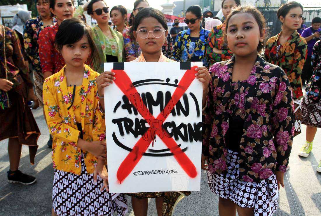 Youths pose with a placard during a protest to mark the World Day against Trafficking in Persons, in Yogyakarta on July 31, 2022