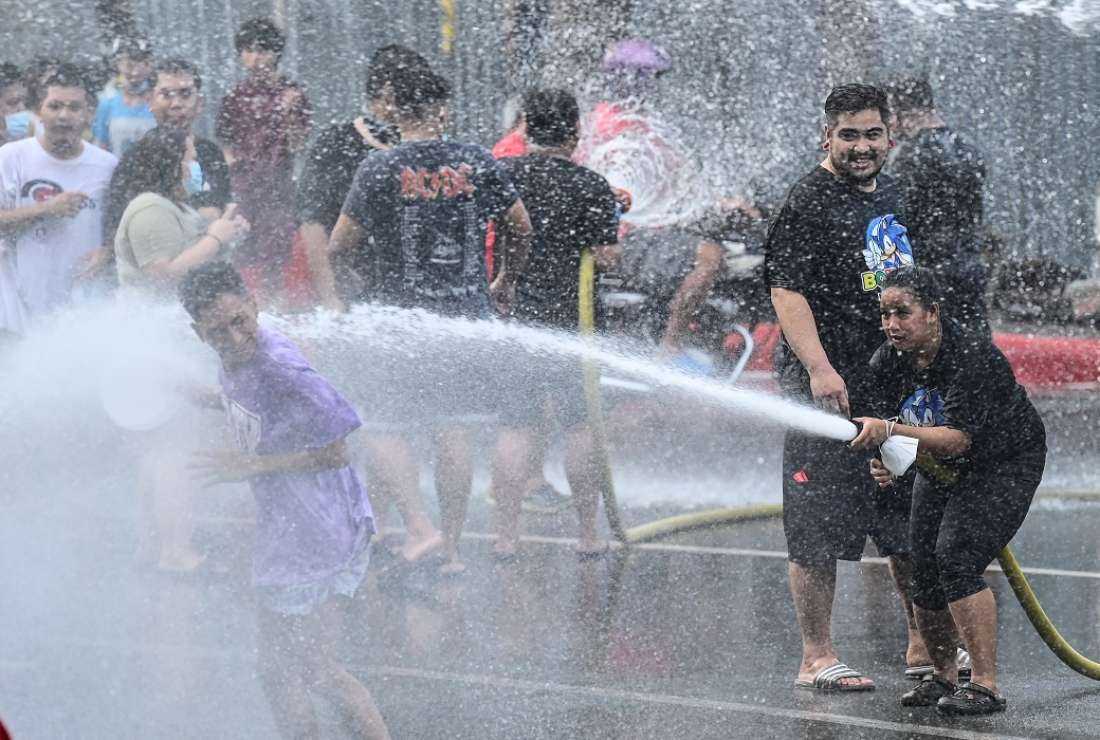 Residents splash and spray water over pedestrians as they take part in celebrations for their patron saint, John the Baptist, in San Juan, Manila on June 24, 2022.  The Philippine capital and its surrounding areas are currently facing severe water shortages brought on by the dry season and the El Nino phenomenon