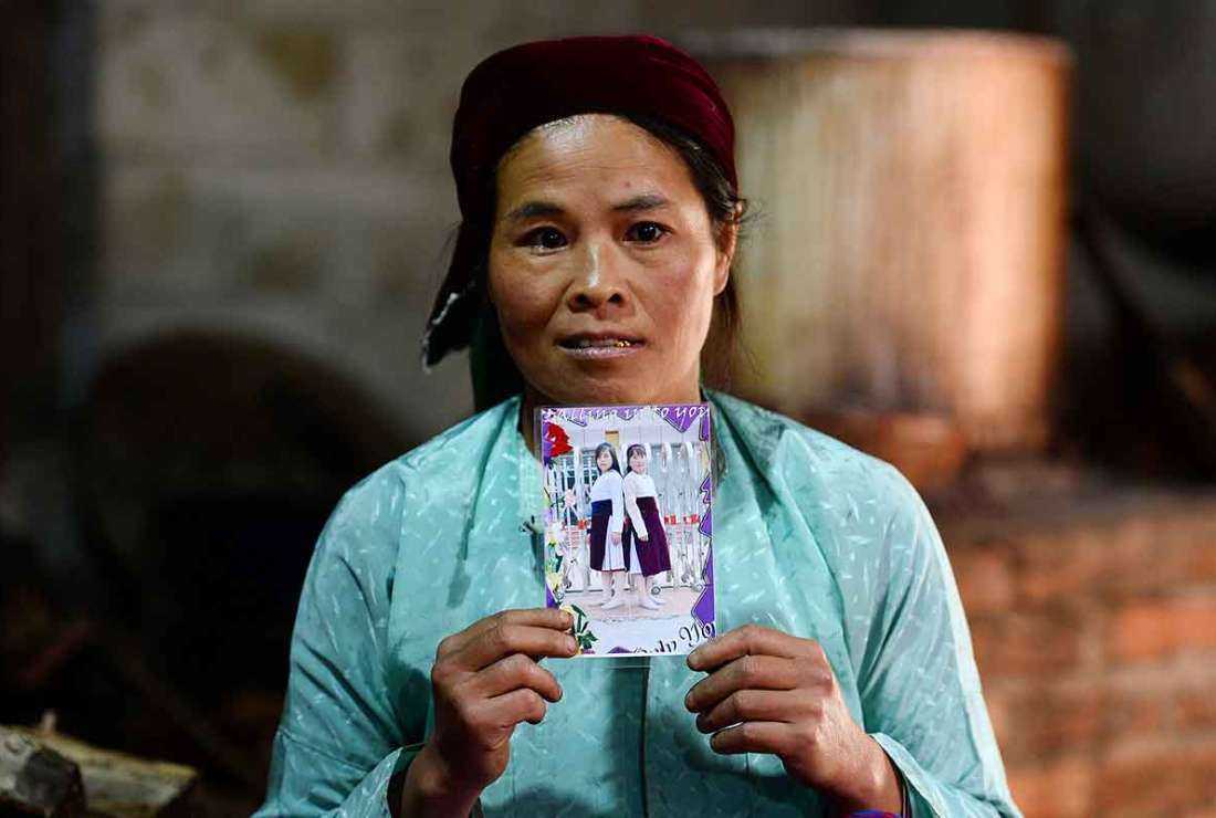 This file photo taken on Oct. 27, 2018, shows Ly Thi My, a Vietnamese mother posing with a photograph of her missing daughter Di at her house in Meo Vac, a mountainous border district between Vietnam's Ha Giang province and China