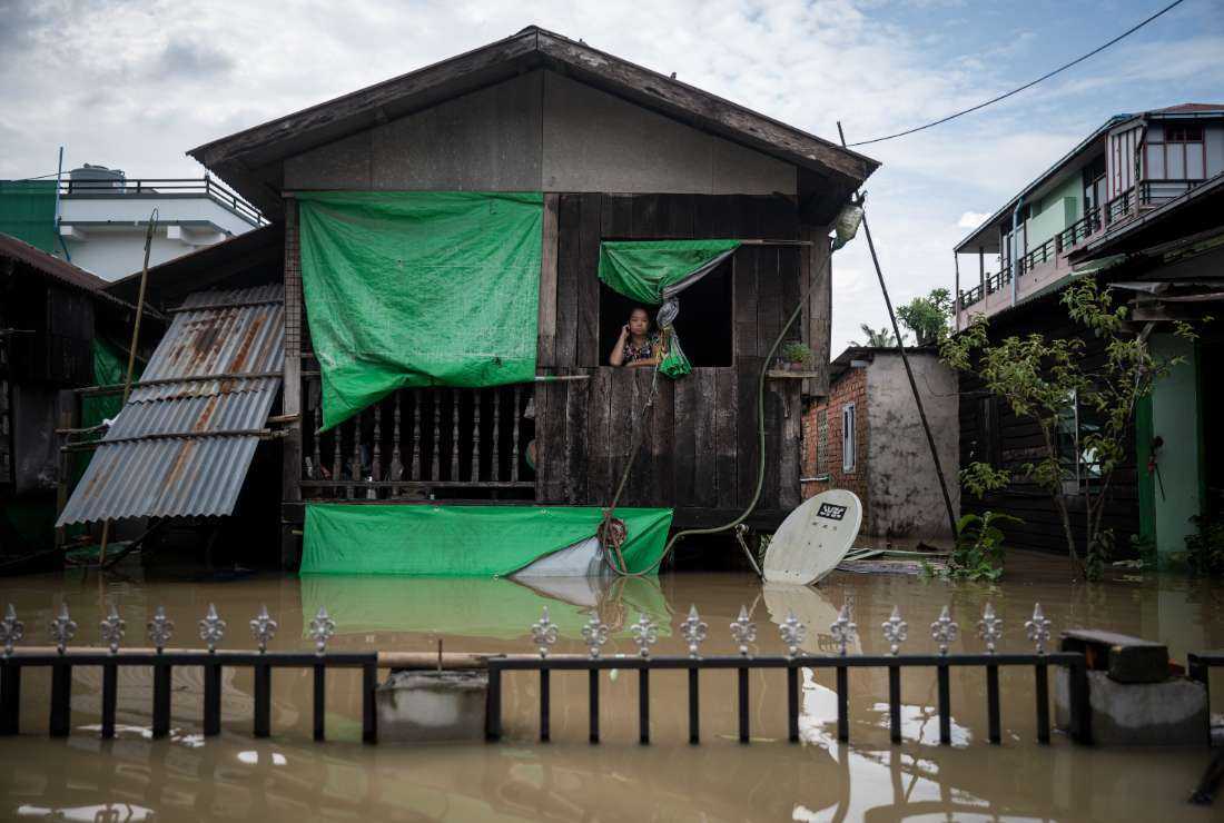 A woman looks out from her house in a flooded area following monsoon rains in Bago township, Bago region, on Aug. 11