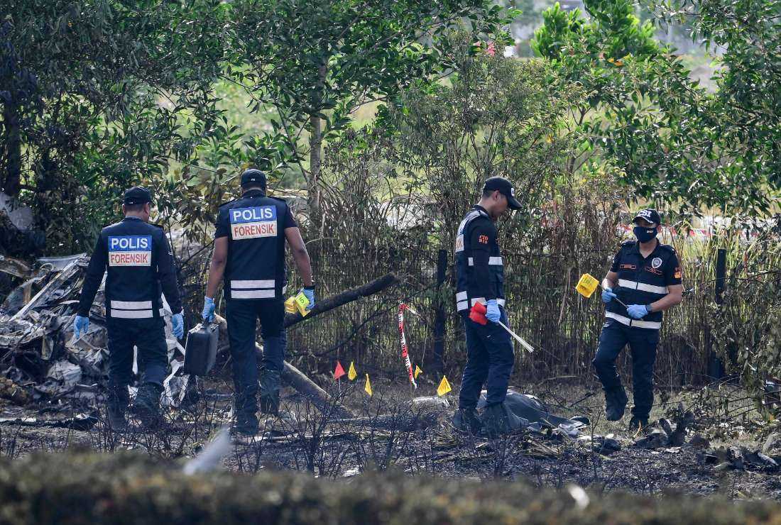 Members of the fire and rescue department inspect the crash site of a plane in Shah Alam, Malaysia's Selangor state on Aug. 17