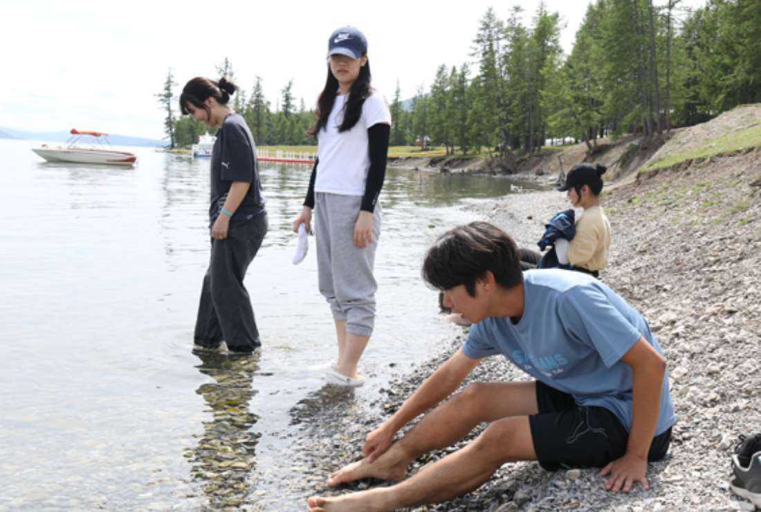 Young Koreans dip their feet in the water of Lake Khovsgol, the largest freshwater lake in Mongolia during their recent trip to the country