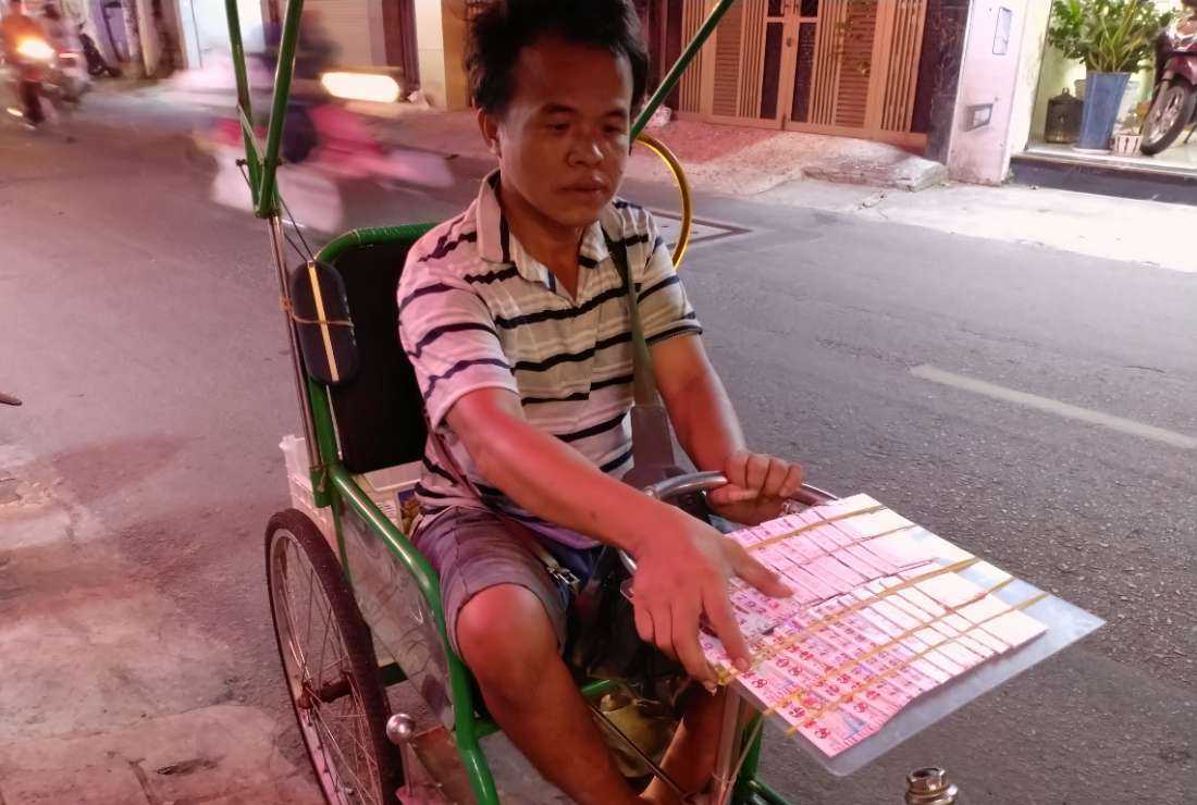 Ly Van Phuong scouts for the next lucky star on a street in Ho Chi Minh City in the night.