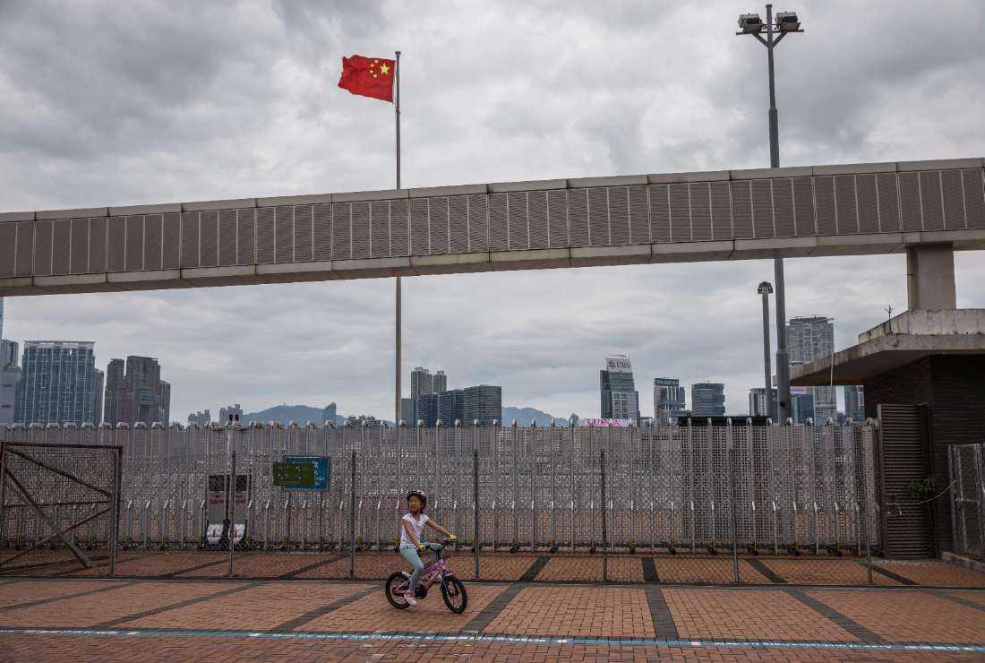 A child cycles past a Chinese national flag in Hong Kong on May 8, 2022. The city has seen a rise in child abuse cases in recent times
