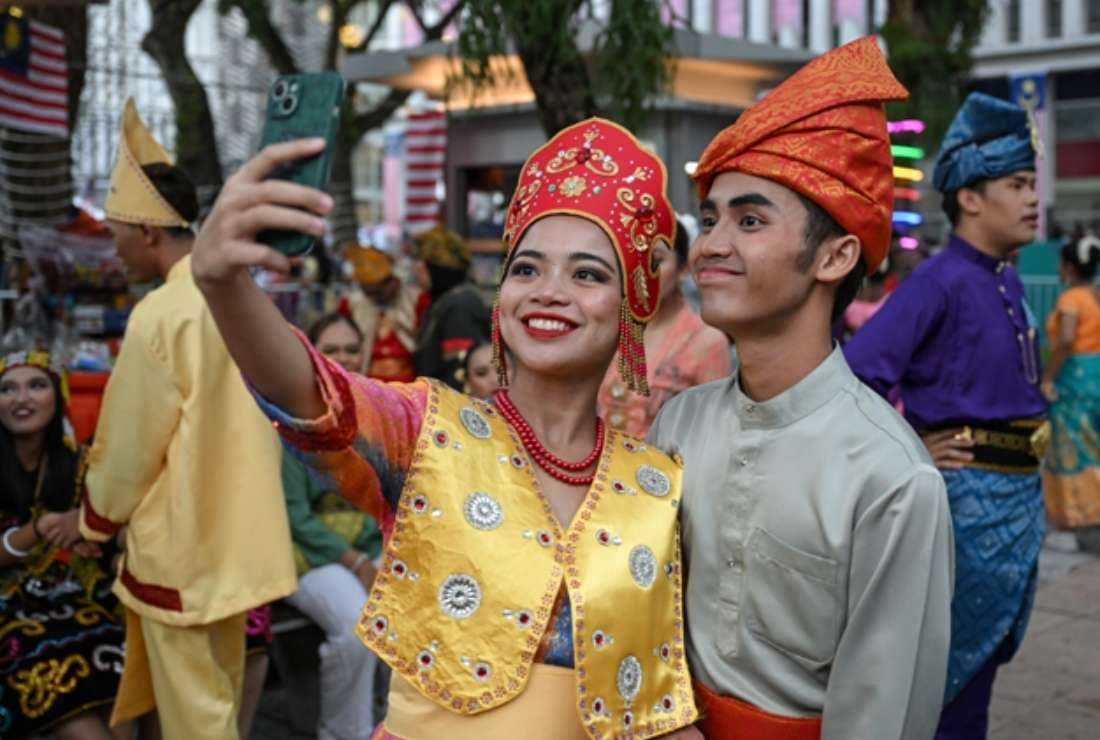 Volunteers wearing traditional Malaysian outfits take a selfie before taking part in the 66th National Day celebrations in Malaysia's administrative capital Putrajaya, on Aug. 31. The country commemorates the Federation of Malaya's independence from British rule in 1957.