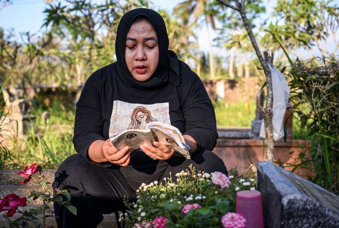 This picture taken on Sept. 21 shows Cholifatul Noor praying at the grave of her only child Jovan Farellino, who was 15 when he died in the stampede that killed 135 people at the Kanjuruhan football stadium on Oct. 1, 2022, in Malang, East Java