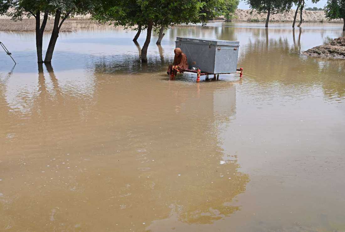 A woman with her belongings wades through the floodwaters at a village in the Okara district of Punjab province on Aug. 28