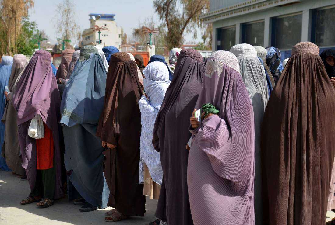 Afghan women stand on a queue to receive food aid distributed by a charity foundation during the Muslim holy fasting month of Ramadan in Kandahar on March 28. 