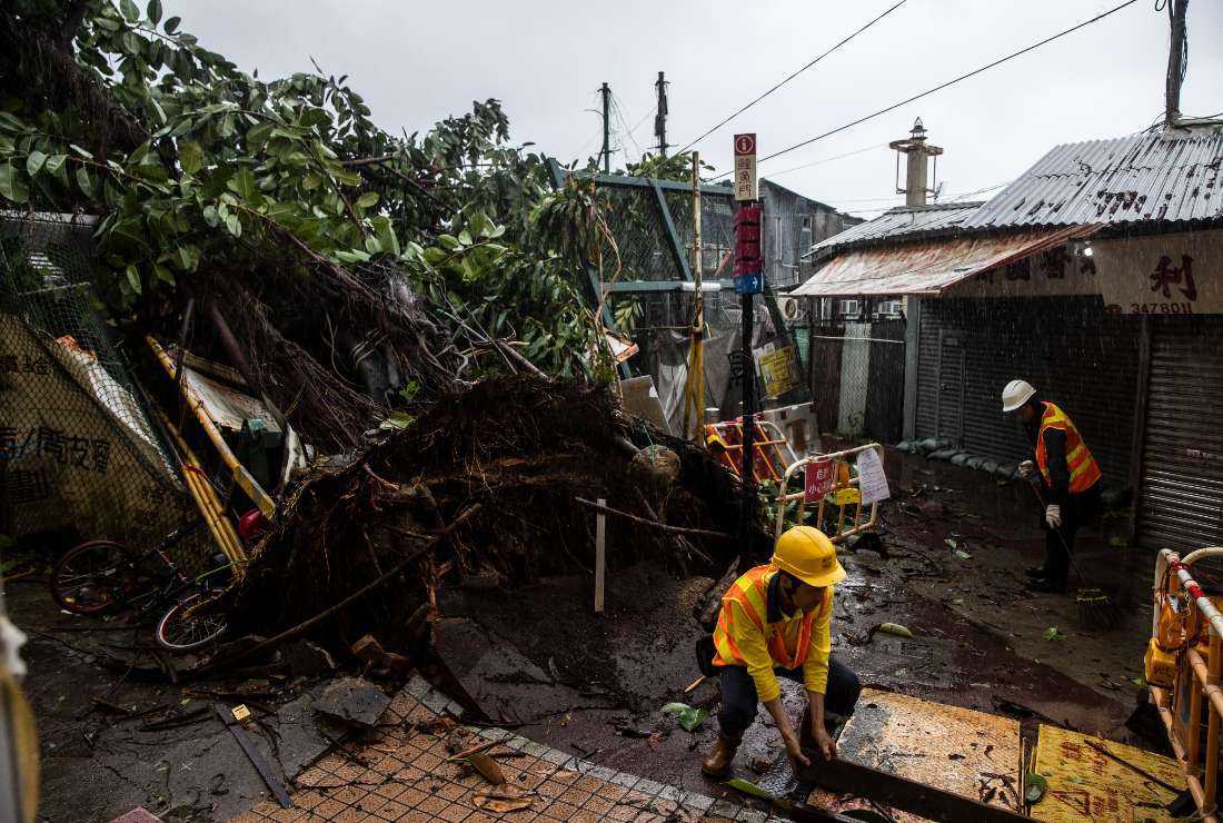 Workers clean up around a fallen tree caused by Typhoon Saola in a village in Lei Yue Mun in Hong Kong on Sept. 2