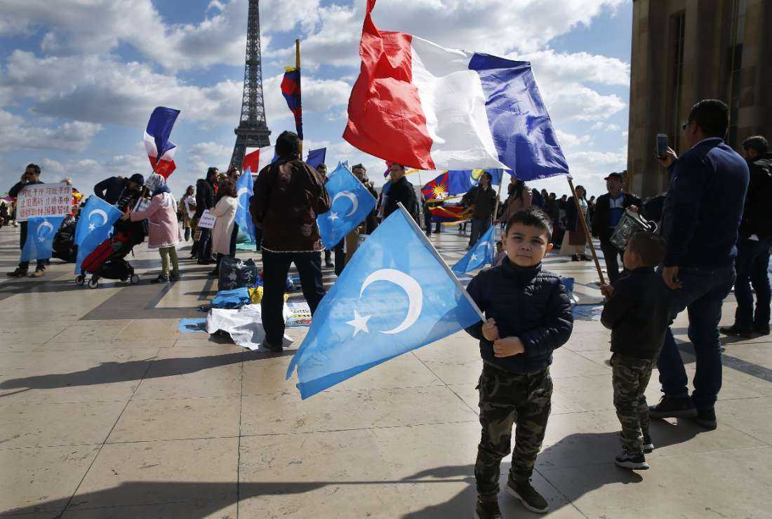 Children and protesters of the French Uyghur Community hold flags of East Turkestan (or Uighur) and France during a demonstration over China's human rights record near the Eiffel Tower on the Trocadero esplanade in Paris on March 25, 2019, during a state visit of the Chinese president.