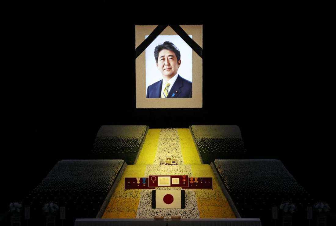 A portrait of former Japanese PM Shinzo Abe is seen during a memorial event. His assassin, Tetsuya Yamagami, said he targeted Abe for promoting the Unification Church, a cult-like organization he blamed for destroying his family