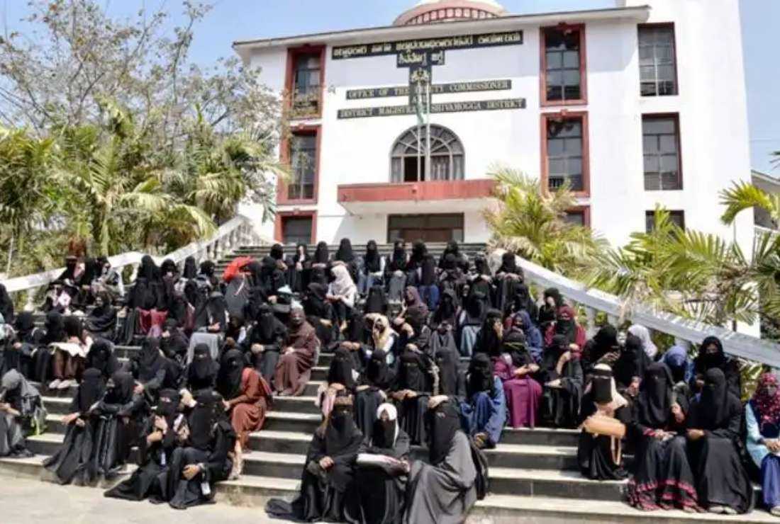 Muslim students and supporters sit in front of the office of the deputy commissioner in a protest against the order banning the hijab in schools and colleges in Shivamogga district in India’s Karnataka state on Feb. 17, 2022 