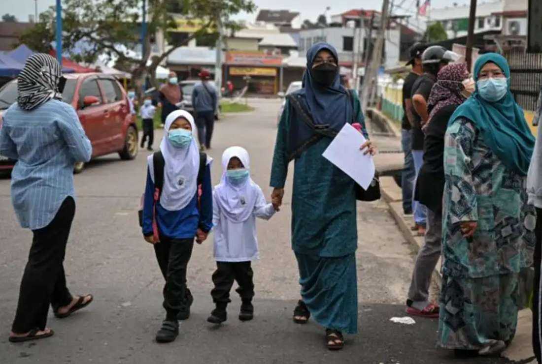 A mother arrives with her daughters on the first day of elementary school in Karak, Pahang state on March 21, 2022. Muslim-majority Malaysia's children are getting involved in different kinds of pro-Palestinian protests during the Palestine Solidarity Week from Oct 29. to Nov. 3 