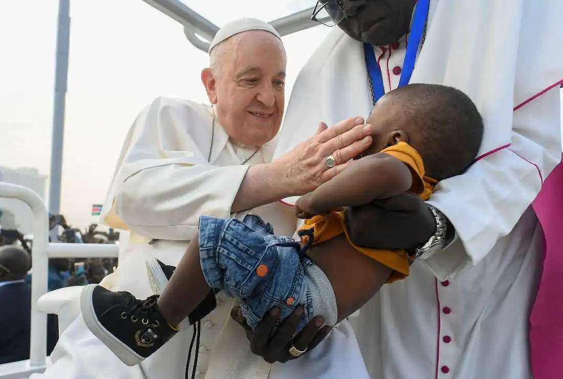 This handout photo taken and released on Feb. 5 by the Vatican Media shows Pope Francis (left) blessing a child during the holy mass at the John Garang Mausoleum in Juba, South Sudan.