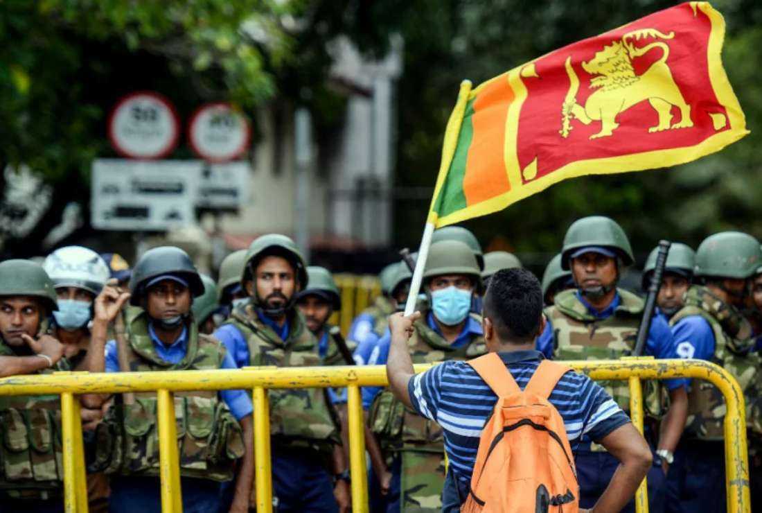A demonstrator waves a Sri Lankan flag near police barricades during a protest march headed to the Presidential secretariat office against Sri Lankan President Ranil Wickremesinghe, in Colombo on July 22, 2022