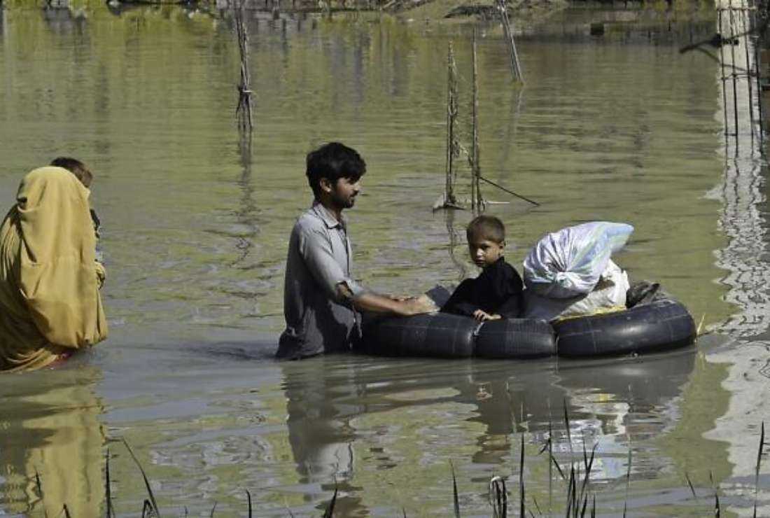 A family wades through a flood-hit area following heavy monsoon rains in Charsadda district of Khyber Pakhtunkhwa, Pakistan on Aug 29, 2022