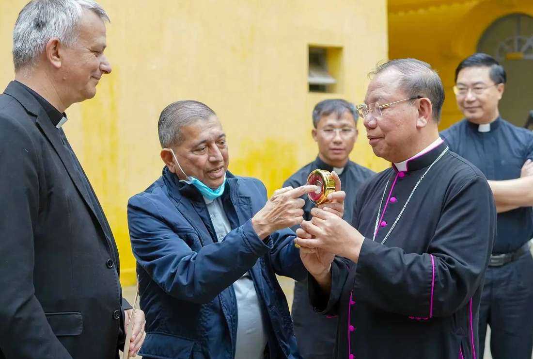 Fathers Vincent Sénéchal (left) and Balthazar Castelino offer Bishop François Pallu’s relic to Archbishop Joseph Vu Van Thien of Hanoi on Oct. 28. 