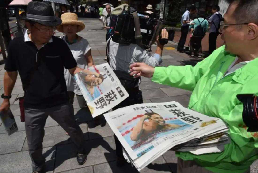 A file picture of a vendor handing out extra edition newspapers to pedestrians in Tokyo on Aug. 7, 2016 