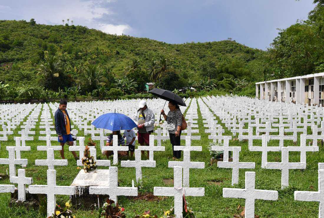 People visit the grave of relatives on the 10th anniversary of the Haiyan Typhoon disaster at a cemetery in Tacloban on Nov. 8