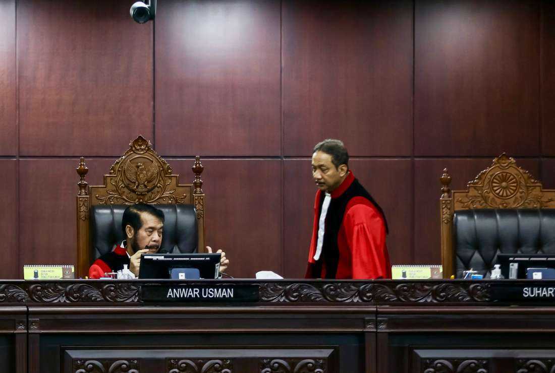 Constitutional Court judges Anwar Usman (left) and Suhartoyo (right) talk to each other during a hearing to rule on a petition to amend the presidential candidature requirement, in Jakarta on Oct. 16.