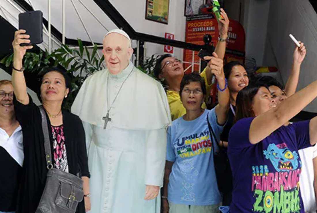 Catholics pose in front of a cardboard stand-up photograph of Pope Francis in suburban Manila ahead of his visit to the country in 2014.