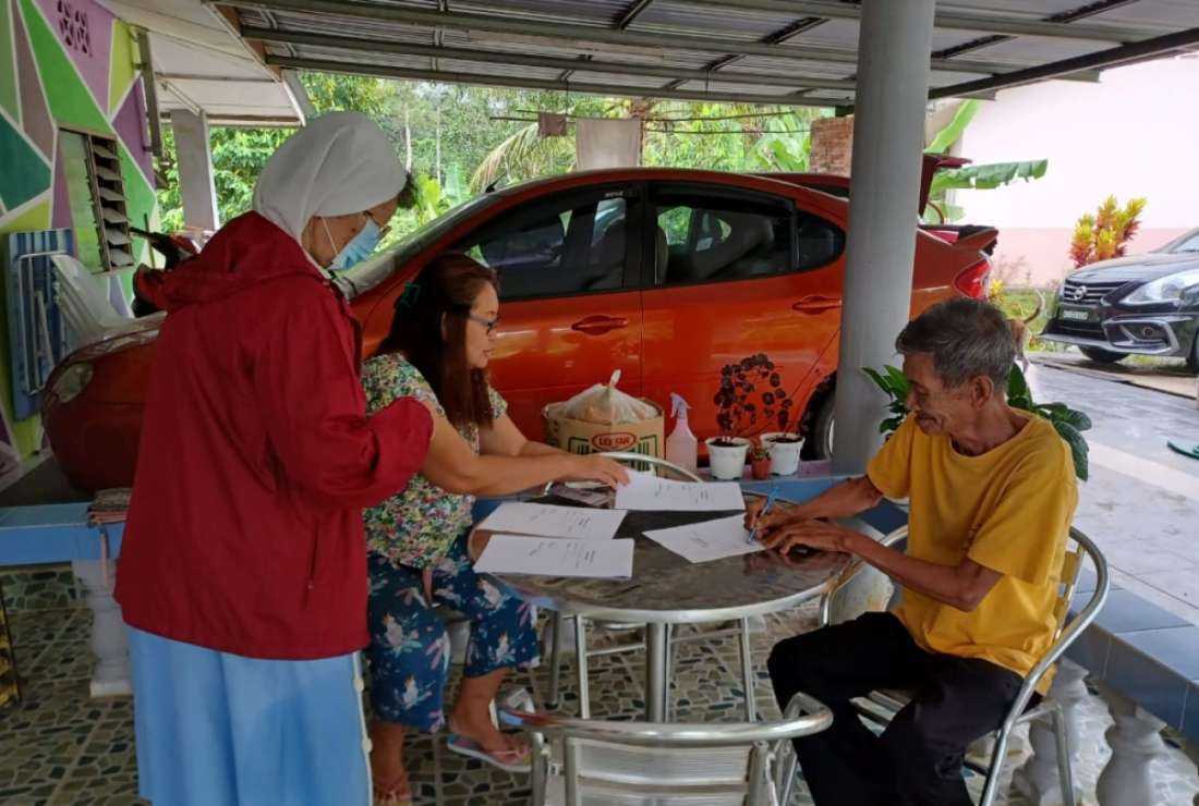 Sister Stella Tan and her team distribute food to a villager during a visit to Bau in Malaysia 