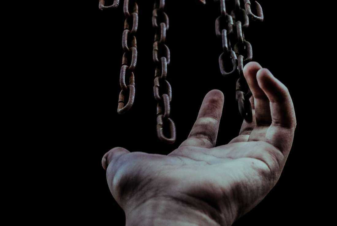  An image shows a hand extended towards chains hanging in the air.