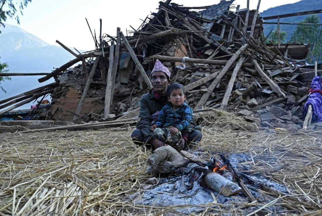 Survivors of a recent earthquake sit in front of a damaged house in Chiuri, a village in Nepal's Jajarkot district on Nov. 5.